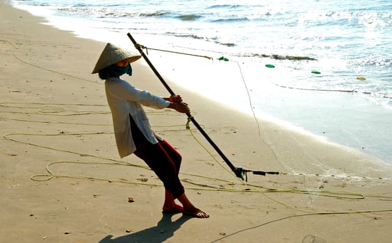 Fisherman's wife hauling in the fishing net,Mui Ne,Vietnam