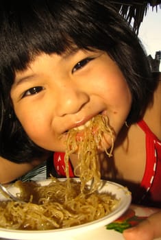 Asian woman eating a noodle dish