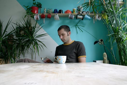 Young man sitting at the table and reading