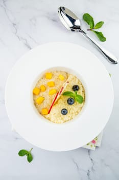 porridge with pieces of apple, mango, berries and mint