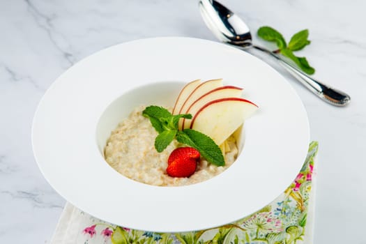 oatmeal with thinly sliced ​​apples, strawberries and mint