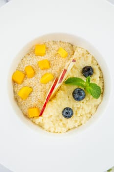 porridge with pieces of apple, mango, berries and mint