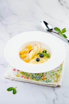 porridge with pieces of apple, mango, berries and mint