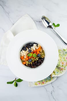 deep plate with cereals, berries, pistachios, dried apricots and raisins