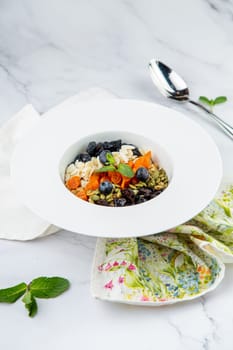 deep plate with cereals, berries, pistachios, dried apricots and raisins