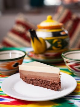 dessert cheesecake three chocolates in an oriental style with a teapot and a cup for tea. High quality photo