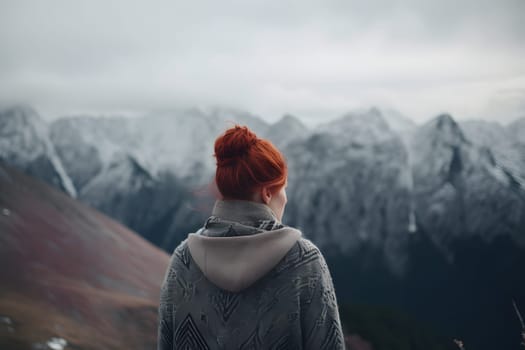Woman with red hair in grey knitted sweater looking to high mountains landscape, view from back. Neural network generated in May 2023. Not based on any actual person, scene or pattern.
