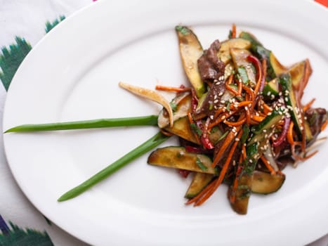 Eastern warm salad. Fried pieces of beef, marcovi and cucumbers in sauce and sesame seeds. Asian style. High quality photo