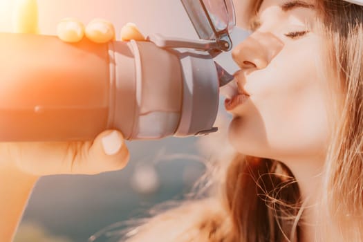 Fintess woman drinking water. Happy, active middle aged woman standing on beach and drinking water after excersise. Concept of lifestyle, sport. Close up.