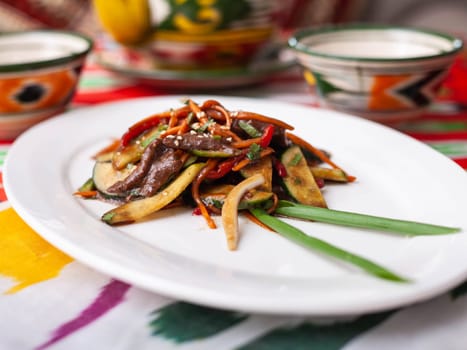 Eastern warm salad. Fried pieces of beef, marcovi and cucumbers in sauce and sesame seeds. Asian style. High quality photo