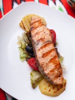 Salmon steak on a pillow of stewed vegetables. Asian style. High quality photo