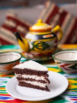 dessert chocolate cake with white butter cream in oriental style on a rooftop with a teapot and a cup for tea. High quality photo