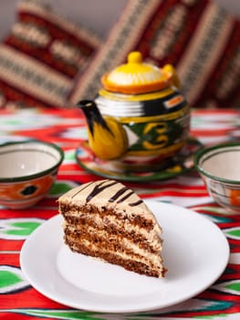 dessert chocolate cake with beige cream in oriental style on a rooftop with a teapot and a cup for tea. High quality photo