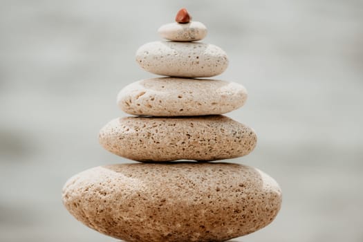 Pyramid stones on the seashore with warm sunset on the sea background. Happy holidays. Pebble beach, calm sea, travel destination. Concept of happy vacation on the sea, meditation, spa, calmness.