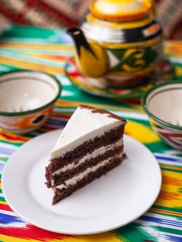 dessert chocolate cake with white butter cream in oriental style on a rooftop with a teapot and a cup for tea. High quality photo