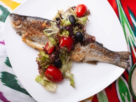 Fried fish with a pillow of stewed vegetables. Asian style. High quality photo