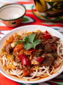 The oriental lagman dish is homemade noodles fried with meat, vegetables and herbs. Eastern cuisine. High quality photo