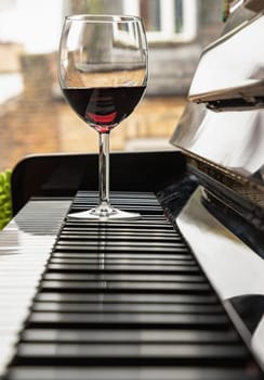 Glass of red wine on piano keyboard. Music and wine concept, Space for text, Selective focus.