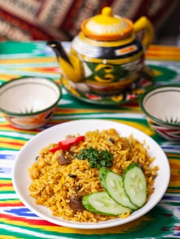 National Uzbek pilaf with meat on the table in the Uzbek style. in oriental style on a table with a teapot and a cup for tea. top view, copy space, flat lay. High quality photo