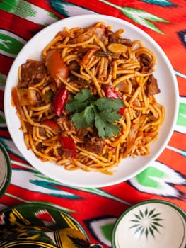 The oriental lagman dish is homemade noodles fried with meat, vegetables and herbs. Eastern cuisine. High quality photo