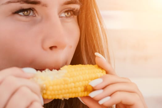 Healthy vegetarian hipster woman in summer outfit eat grilled corn and look to camera. Sexy lady on sea beach sunset or ocean sunrise. Travel, explore, active yoga and meditation lifestyle concept.