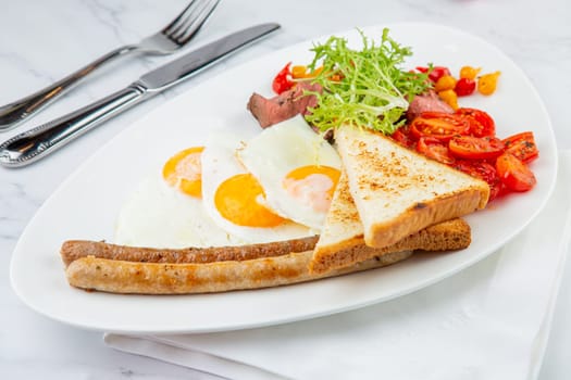 scrambled eggs with vegetables, cherry tomatoes, bread, herbs and sausages