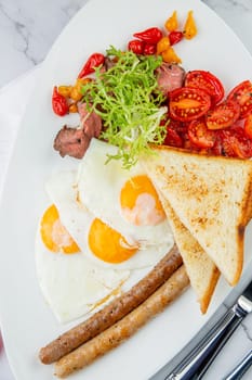 scrambled eggs with vegetables, cherry tomatoes, bread, herbs and sausages