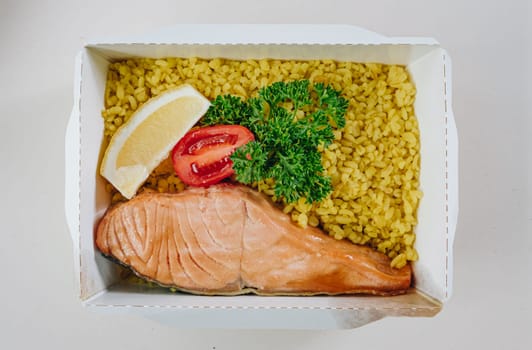 food in containers. proper nutrition, daily diet, weight loss. greens, tomato, lemon salmon steak with couscous side dish.