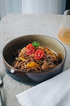 noodles with beef, vegetables, cherry tomatoes and sesame sauce