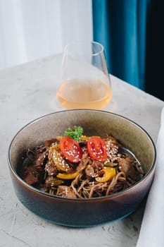 noodles with beef, vegetables, cherry tomatoes and sesame sauce