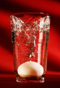 Burning candle in a glass of water