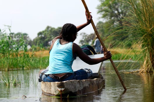 Young woman in mokoro dugout canoe returning to village from shopping in the city,Okavango Delta,Botswana