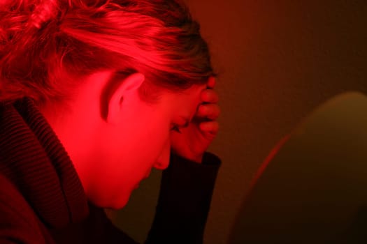 Young woman is irradiated by red light