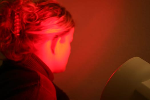 Young woman is irradiated by red light