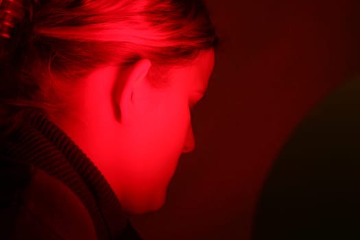 Young woman is irradiated by red light