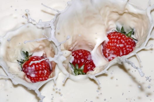 Strawberries fall into milk