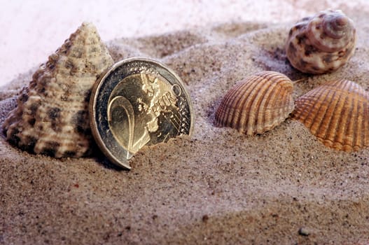 golden shiny 2 Euro piece with sand and shells as symbolism for holiday pay / holiday fund