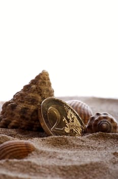 golden shiny 2 Euro piece with sand and shells as symbolism for holiday pay / holiday fund