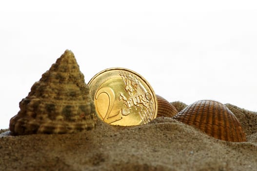golden shiny 2 Euro piece with sand and shells as symbolism for holiday pay / holiday fund