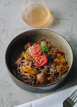 noodles with beef, vegetables, cherry tomatoes and sesame sauce