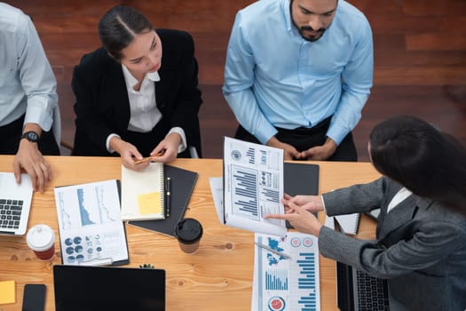 Top view multiracial analyst team use BI dashboard data to analyze financial report on meeting table. Group of diverse business people utilize data analysis by FIntech for business decision. Concord