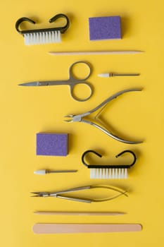 Professional manicure tools on yellow background. Manicure set. Top view. Cuticle pusher, cuticle trimmer and purpose scissor. Set of manicure and pedicure tools and cosmetics with space