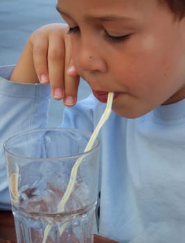 Child with water glass and drinking straw