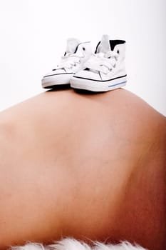 Baby shoes on mother's belly