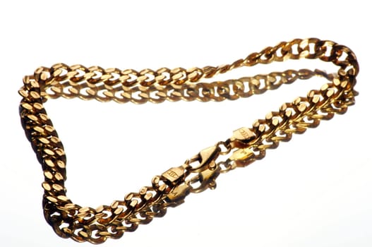 a gold bracelet on a mirror plate exposed against a white background