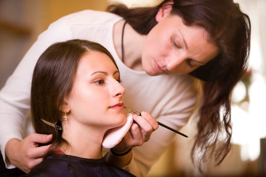 Woman doing make-up with make-up artist