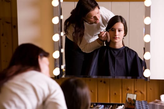Woman doing make-up by make-up artist IV