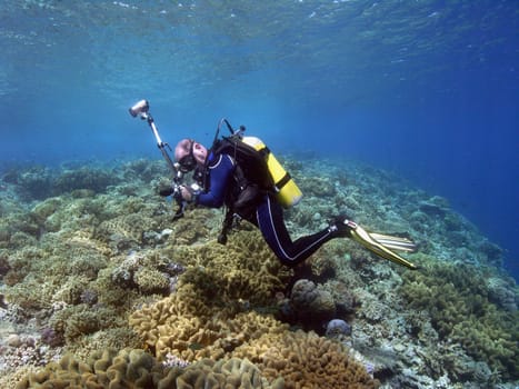 Photographer with housing for SLR camera,fisheye and flash units over the corals near Sulawesi / Indonesia.
