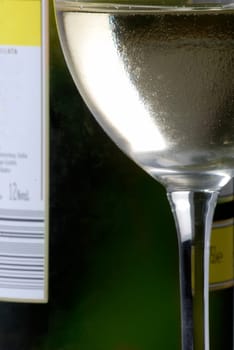 Cold wine glass in front of wine bottle