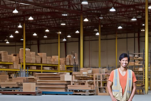 smiling asian male worker standing in a warehouse. Neural network generated in May 2023. Not based on any actual person, scene or pattern.